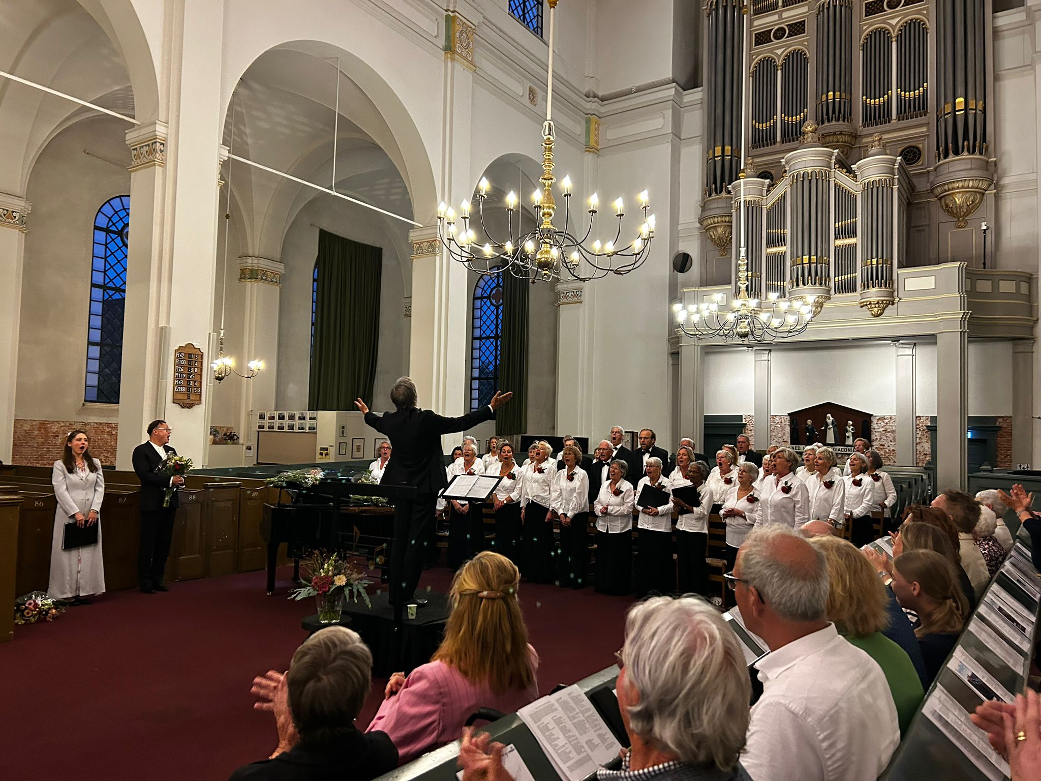 Solisten, dirigent en koor op één foto.